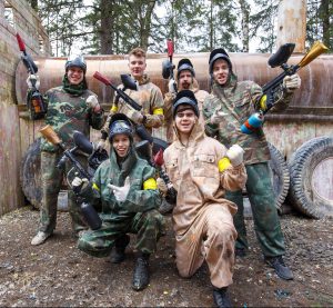 group of friends posing with paintball markers and equipment